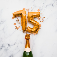 Champagne bottle with gold number 75 balloon. Minimal party anniversary concept