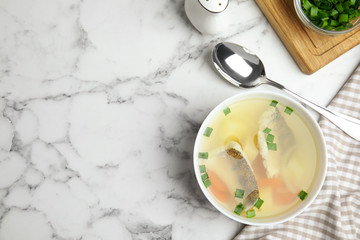 Delicious fish soup served on marble table, flat lay. Space for text