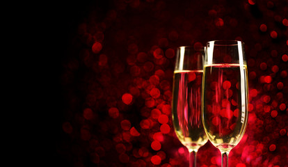 Two champagne glasses on sparkling red bokeh background. Valentine's day dinner invitation. Christmas and new year holiday party.