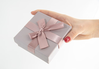 Female hand holds a gift box on a light background.