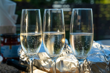Sparkling white wine glasses and foil wrapped barbecue on a table. Dinner party at homes  terrace.
