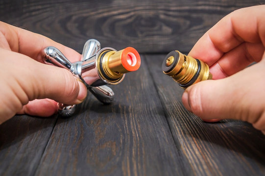 Cruciform hot and cold water main switch of spare parts holding in his hands master plumber