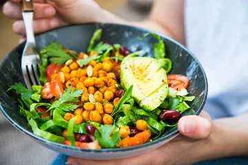 Poster Clean eating, vegan healthy salad bowl closeup , woman holding salad bowl, plant based healthy diet with greens, chickpeas and vegetables © marrakeshh