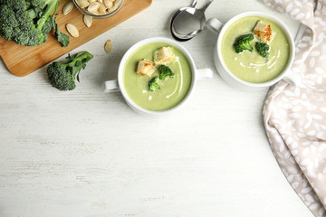 Delicious broccoli cream soup with croutons served on white wooden table, flat lay. Space for text