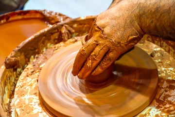 Hands of a potter, creating an earthen jar on the circle. Round in shape and a complete earthen cup...