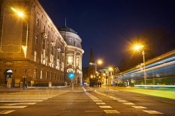 Street and facade of a baroque building during the night in Poznan.