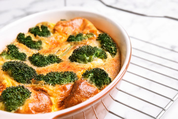 Tasty broccoli casserole in baking dish on cooling rack, closeup