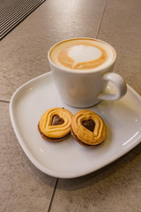A Cup of hot latte art coffee with cookies
