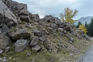 Fototapeta na wymiar Harsh rock formations creating rough hill next to gravel road with fall colors