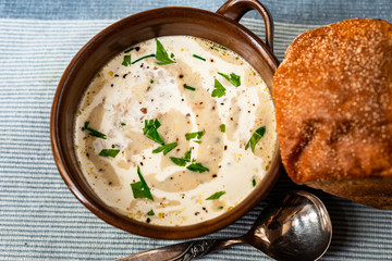 White creamy soup in bowl, bread.
