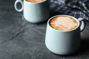 Cups of delicious hot cocoa on grey table. Space for text