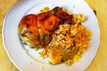 Baked chicken leg with turmeric rice on plate.
