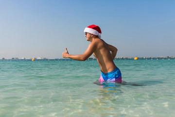 Young man in santa hat running in sea water, Vocation.