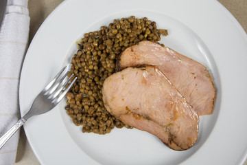 slices of roast pork and lentils on a plate