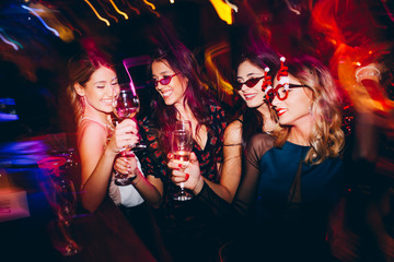 Female friends drinking wine and celebrating new year at the club