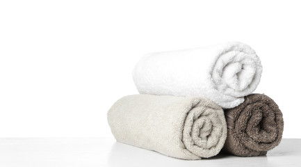 Fototapeta na wymiar Rolled fresh clean towels for bathroom on table against white background. Space for text