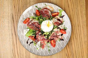 Delicious prosciutto salad with vegetables served on wooden table, top view