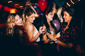 Female friends drinking wine and celebrating new year at the club - obrazy, fototapety, plakaty