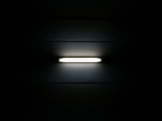 Light bulbs under the ceiling at night, fluorescent light tube on the dark wall, The light illuminating in the black background.