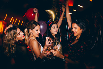 Female friends drinking wine and celebrating new year at the club - obrazy, fototapety, plakaty