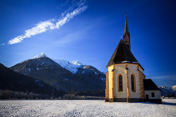 Fototapeta na wymiar An old church on the top of the mountain in italian alps during winter season