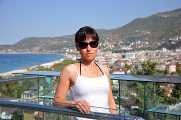 Beautiful woman on the background of the resort town by the sea. Sea bay.