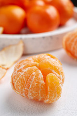 Peeled ripe tangerine on white table, closeup