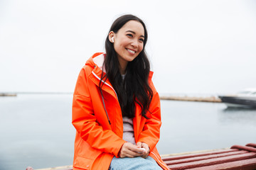 Obraz premium Smiling attractive young asian woman wearing raincoat