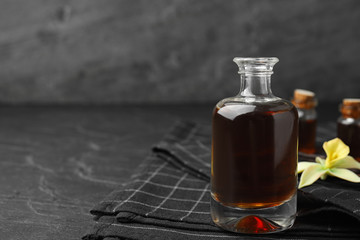 Aromatic homemade vanilla extract in glass bottle on table. Space for text