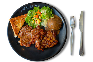 steak,salad,mashed potato and  garlic bread in black plate with fork and knife isolated on white