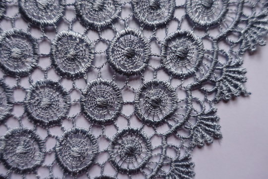 Closeup of edge of grey lace with circular pattern