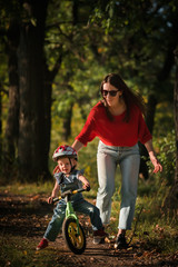 Fototapeta na wymiar mother and daughter. Balance bike. Cycling in park.