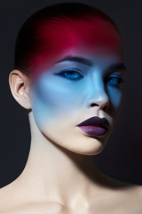 Bright contrasting beauty makeup portrait of a woman in blue and red shadow tones. Perfect clean skin and face makeup, dark lipstick on plump lips