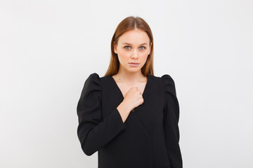 elegance woman in black dress isolated on white background. girl having serious confident look, showing clenched fist. Feminism, equality and women's liberation