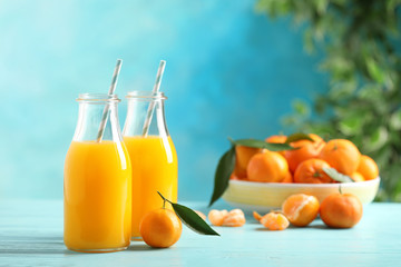 Bottles of fresh tangerine juice on blue wooden background. Space for text