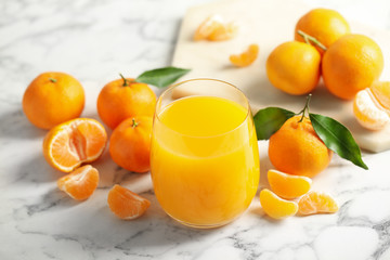 Glass of fresh tangerine juice and fruits on marble table