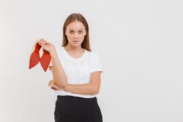 Young woman holding high heel shoe in hand. girl in white t-shirt isolate on white.