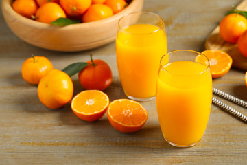 Glasses of fresh tangerine juice and fruits on wooden table