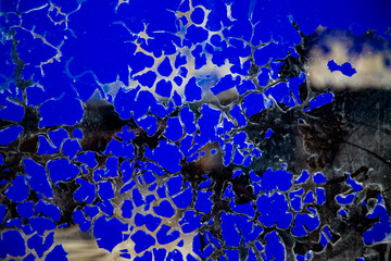 Abstract background of cracked blue paint on a dirty glass.
