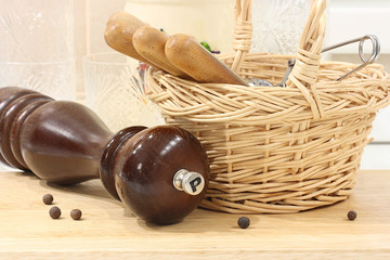 Pepper mill on the background of a wicker basket with cutlery