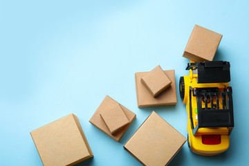 Top view of toy forklift with boxes on blue background, space for text. Logistics and wholesale...