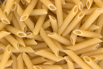 Italian pasta penne uncooked background.