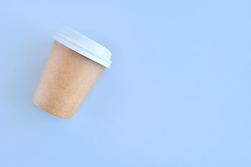 Recycling craft paper cup of coffee to go on neutral background with copy space. Selective focus. Craft cup for hot beverage, takeaway. Disposable cup. Eco package. Cardboard coffee cup