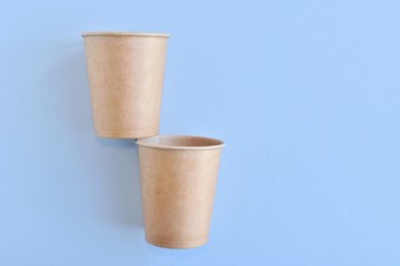 Recycling craft paper cup of coffee to go on neutral background with copy space. Selective focus. Craft cup for hot beverage, takeaway. Disposable cup. Eco package. Cardboard coffee cup