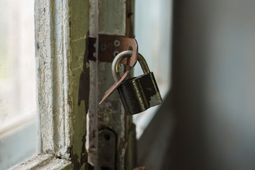 Old master key lock, rusty close padlock on wooden door in an old abandoned house. Close up...