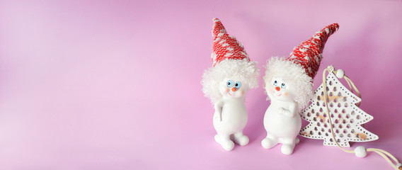 Banner with two funny cute white snowman with white Christmas trees on a pink background with copyspace. Christmas and New Year concept, minimalism