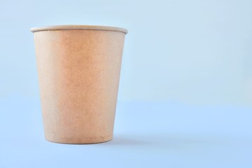 Recycling craft paper cup of coffee to go on neutral background with copy space. Selective focus. Craft cup for hot beverage, takeaway. Disposable cup. Eco package. Cardboard coffee cup