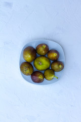 ripe figs in a white plate on a white wooden background. the view from the top. space for text. the concept of healthy eating. live vitamins. fresh berries.