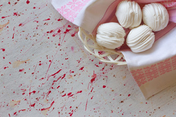 Homemade marshmallows on a white wooden table in a basket.  Pink sweet homemade marshmallow or meringue. top view dessert image. four white cakes . the concept of baking and cooking for the cafe.