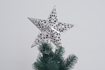 Christmas decorative beautiful silver metal star on the top of A Christmas tree. Holiday mood